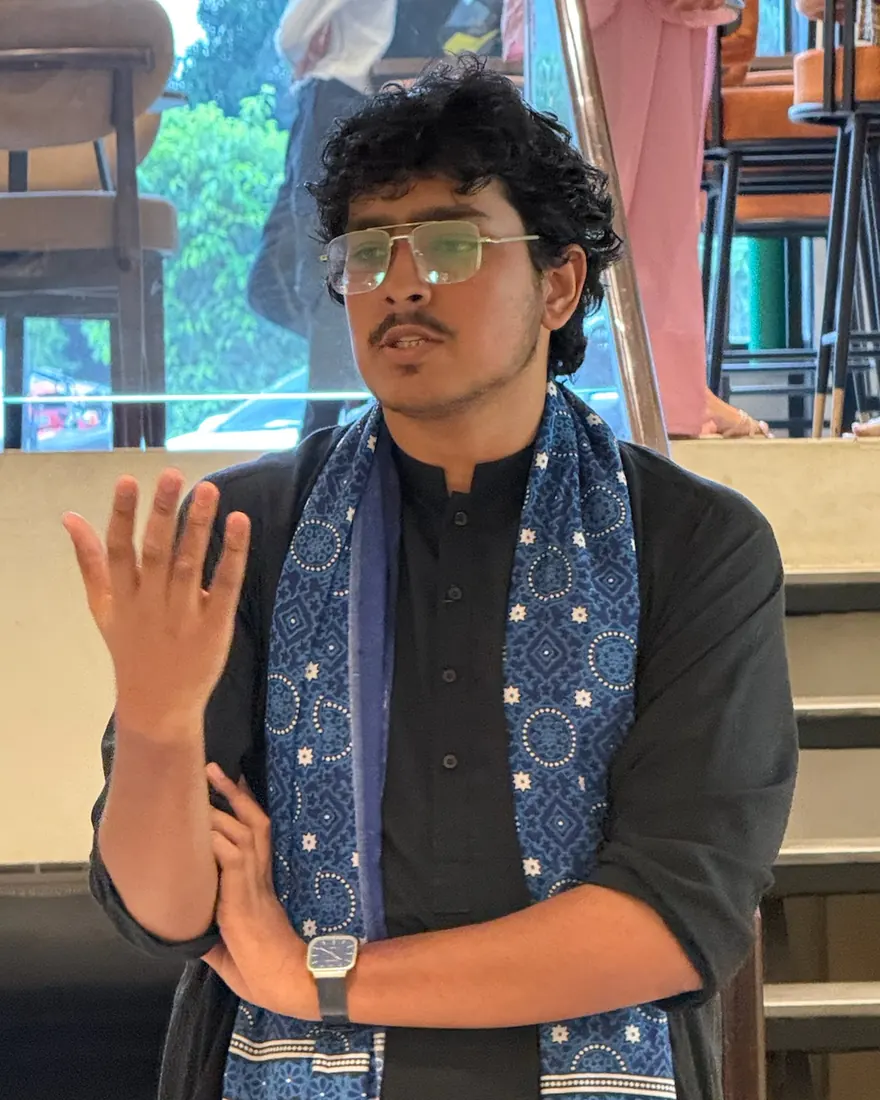 Faseeh speaking at UnMixer in a black kurta and blue ajrak scarf
